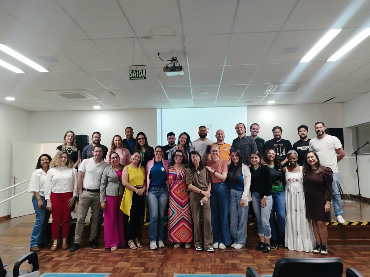 Foto em grupo com cerca de 30 servidores do campus e a palestrante, todos em p&eacute; e sorrindo, posicionados no palco do audit&oacute;rio ap&oacute;s o evento.